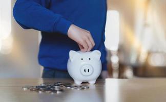 niño de la escuela poniendo monedas en la alcancía, niño niño contando ahorrar dinero, niños aprendiendo responsabilidad financiera y planeando ahorrar dinero para el futuro o la educación foto