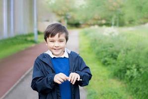 Cute School kid holding dandelion flower in spring park while walking to school in the morning. Happy child boy having fun outdoors. photo