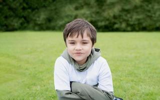 Outdoor portrait handsome young boy making funny or smiling face, Healthy kid with a happy face standing alone in the park, Positive child playing outside in Spring or Summer Holiday photo