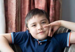 Portrait Happy boy sitting on sofa looking at camera with smiling face, Positive Child resting in living room with light shining from window on sunny day spring,summer.Kid relaxing at home on weekend photo