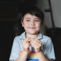 Happy kid looking out with smiling face, Child playing alone  in living room, Selective focus Child boy holding one pound coin looking out ,  Children learning to save money for studying or future photo