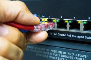 Technician connect cable network to switch port in server room , Concept internet network management