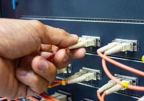 Technician connect fiber cable network to switch port in server room , Concept internet network management