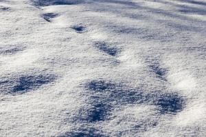 footprints and dents in the snow after people passed photo