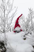un pequeño juguete sentado en la nieve con ropa roja foto