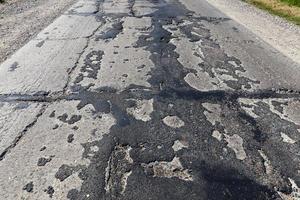 a bad asphalt road that has been repaired many times photo