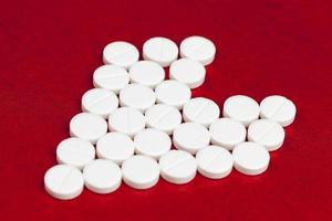 medical medicines tablets stacked on a red background in the shape of a heart photo