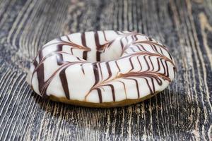 a fresh doughnut covered with white chocolate , closeup photo