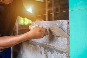 Close-up shot of a bricklayer building a house or walls with mortar and bricks photo