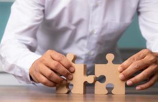 Businessman hand connecting jigsaw puzzle on desk, Business solutions. photo