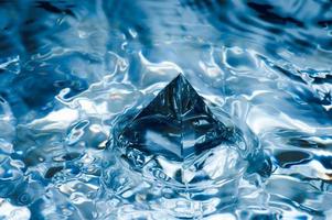 Abstract blue background with water splashen and a geometric object. Pyramid in water. photo