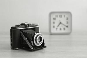 Vintage analog medium format film camera and a clock in black and white. Old film camera with bellows. photo