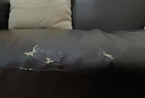 sofá negro de cuero viejo roto. falta de asiento de cuero viejo debido a una larga vida útil foto