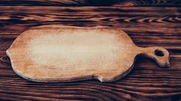 Wooden cutting board on brown table background photo