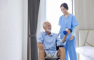 Hospice nurse is helping Caucasian man in wheelchair to exercising muscle strength in pension retirement center for home care rehabilitation and post treatment recovery process photo