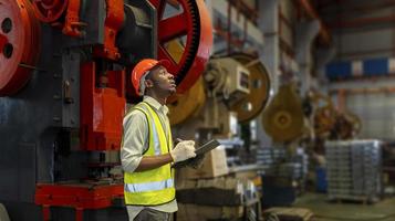 trabajador industrial afroamericano está usando portapapeles para tomar nota mientras inspecciona dentro de la fábrica de techos galvanizados de chapa metálica para la industria de seguridad y el concepto de control de calidad foto