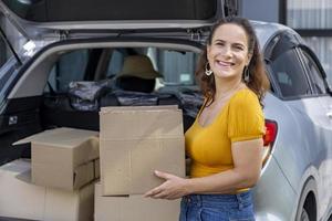 mujer madura caucásica está sosteniendo una caja de cartón para empacar dentro del automóvil para el concepto de mudanza y reubicación de la casa foto
