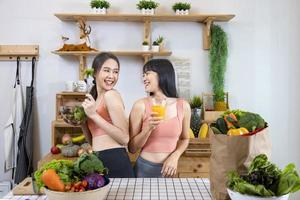 Asian sister is having a healthy food and drink while helping each other cooking in kitchen for vegan, vegetarian and plant based ingredient concept photo