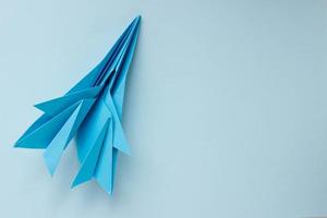 avión de origami de papel azul sobre un fondo azul claro. fondo con lugar para texto foto