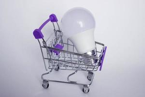 Mini decorative shopping cart with LED lamp on white background with copy space photo