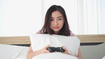 Excited young gamer girl sitting and playing video games on console.