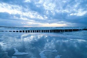 sunset on the beach of the Baltic Sea. Reflection on the beach. Groynes reach into the sea. photo