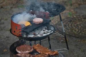 Grill with coal, grate and meat. Burger with cheese in the preparation on the grill photo