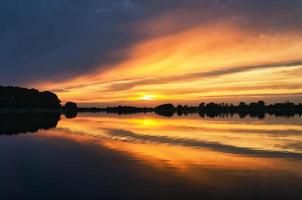 reflejo del cielo en el agua. los colores dorado, amarillo y rosa del cielo se reflejan en el lago. foto