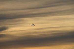 airplane in the evening sky in luminous horizon. photo