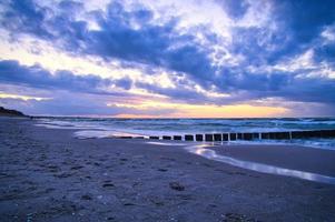 puesta de sol en la playa del mar báltico. los espigones llegan al mar. hora azul foto