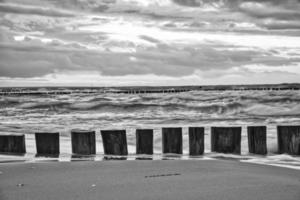 sunset on the beach of the Baltic Sea in black and white. Groynes in front of the sea and sky. photo