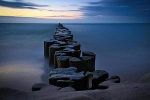 espigones que sobresalen en el horizonte en el mar Báltico. larga exposición con colores apagados foto