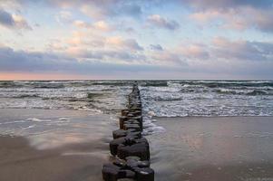 groynes on the beach of the Baltic Sea in Zingst. Waves break on the wood photo