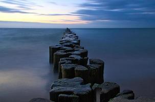 espigones que sobresalen en el horizonte en el mar Báltico. larga exposición con colores apagados foto