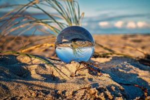 Glass globe on the beach of the Baltic Sea in Zingst in which the landscape is depicted. photo