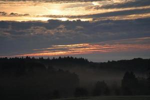Rising sun on foggy meadow in the morning in Saarland. The sky seems to burn photo