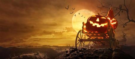calabazas de halloween en un vagón de granja pasando por una tumba de carretera estirada hasta el castillo espeluznante en la noche de luna llena y murciélagos volando foto
