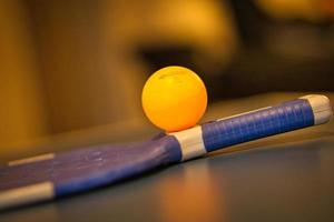 Table tennis bat with ball on a table tennis table. Pause before the game. photo