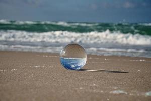 Glass globe on the beach of the Baltic Sea in Zingst in which the landscape is depicted. photo