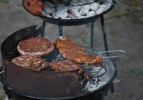 Grill with coal, grate and meat. Burger with cheese in the preparation on the grill photo