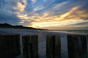 sunset on the baltic coast with clouds in the sky and groynes photo