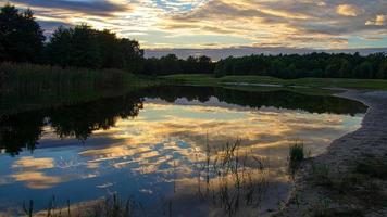 Forest lake with reflection of the sky at sunset photo