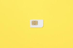 Subscriber identity module. White SIM card on yellow background photo
