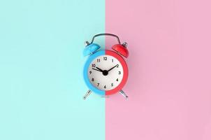 A small alarm clock is located between the blue and red background areas photo