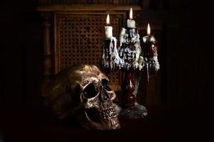 Old battered skull lies with an antique wooden candlestick photo