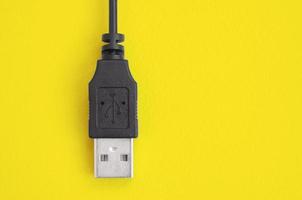 Black USB plug lies on a bright yellow background. photo