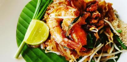 Close up stir fried with rice noodle, river prawn or shrimp, bean sprout, sliced chives and lime on banana leaf. Famous food in Thailand call Pad Thai. Selective focus technique. photo