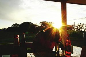 silueta de hombre con botella de cerveza y luz del sol brillando temprano en la mañana. foto