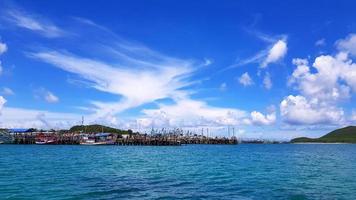Many fishing boat parked on sea at port near coast and community with blue sky, white clouds and green mountain background and copy space. Landscape of ocean or seascape. Beautiful view and nature
