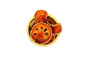 Many sliced of dry bael fruit on the wooden bowl isolated on white background. Fruit or Herb concept photo